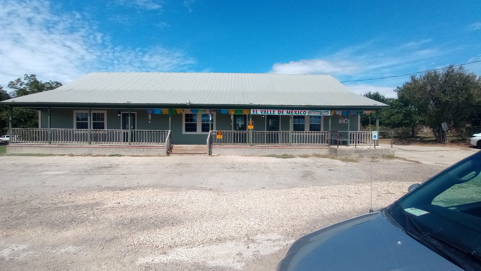 El Valle De Mexico restaurant exterior with green metal roof and papel picado banners on TX-106 Loop in San Antonio